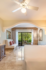 Interior de habitación con balcón y vista a los jardines en hotel Iberostar Waves.