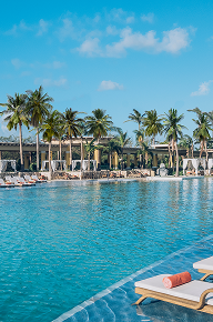 Piscina exterior de lujo rodeada de palmeras en el hotel JOIA by Iberostar.