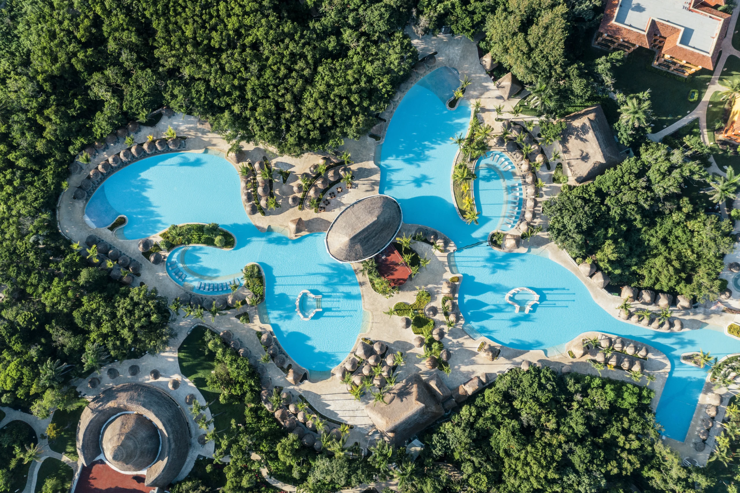 Complejo de piscinas serpenteantes entre jardines y vegetación en Iberostar Waves Paraíso del Mar.